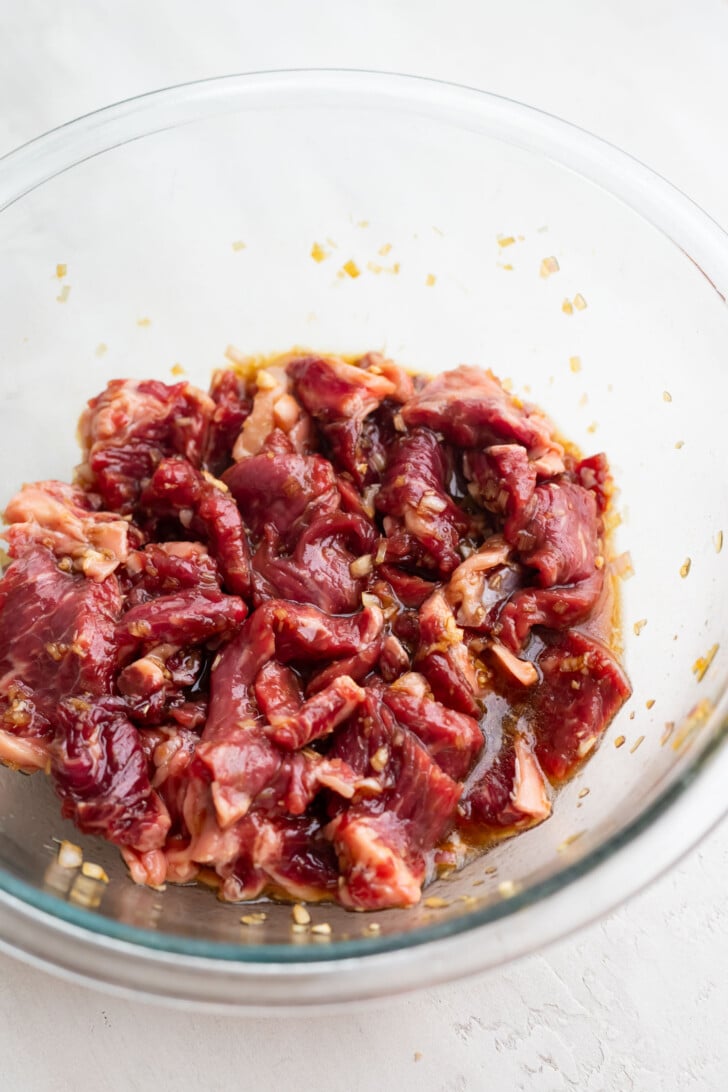 Steak marinating in a mixing bowl.