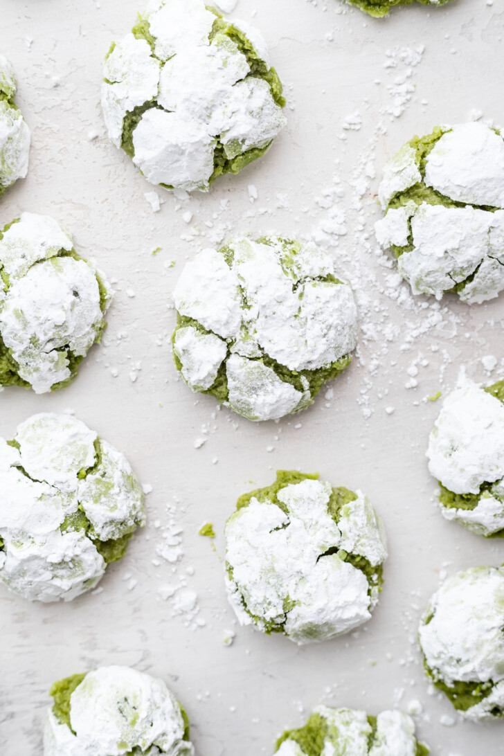 Matcha crinkle cookies on a white table.