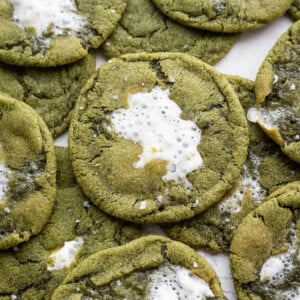 Matcha hot chocolate cookies stacked on top of each other on a white table.