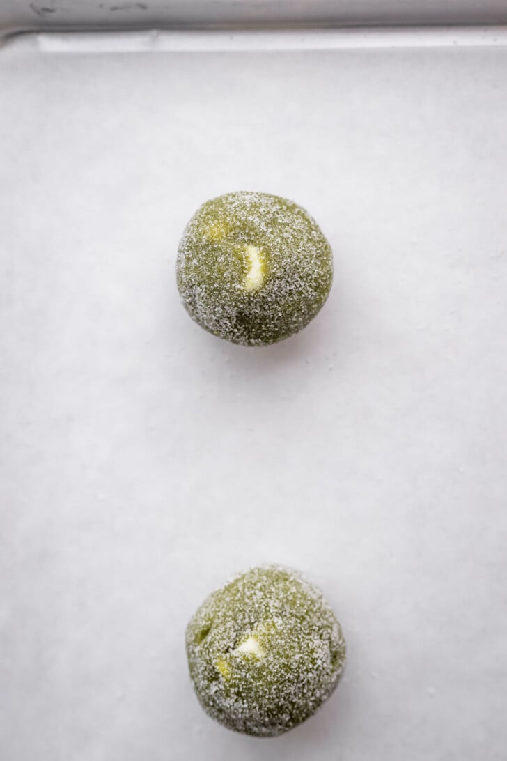 Matcha hot chocolate cookie dough balls on a baking sheet.
