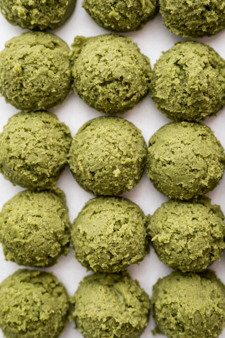 Scooped matcha cookie dough on a baking sheet.