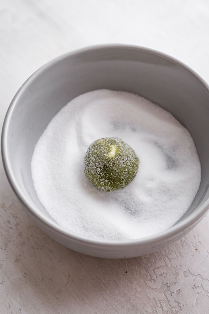 Matcha cookie dough ball coated in sugar.