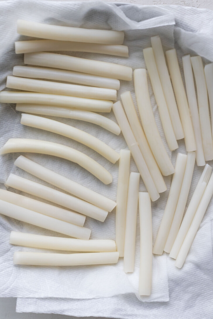 Drying pickled lotus root stems on paper towels.