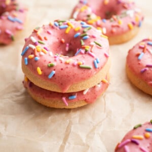 Baked strawberry mochi donuts stacked on each other on parchment paper.