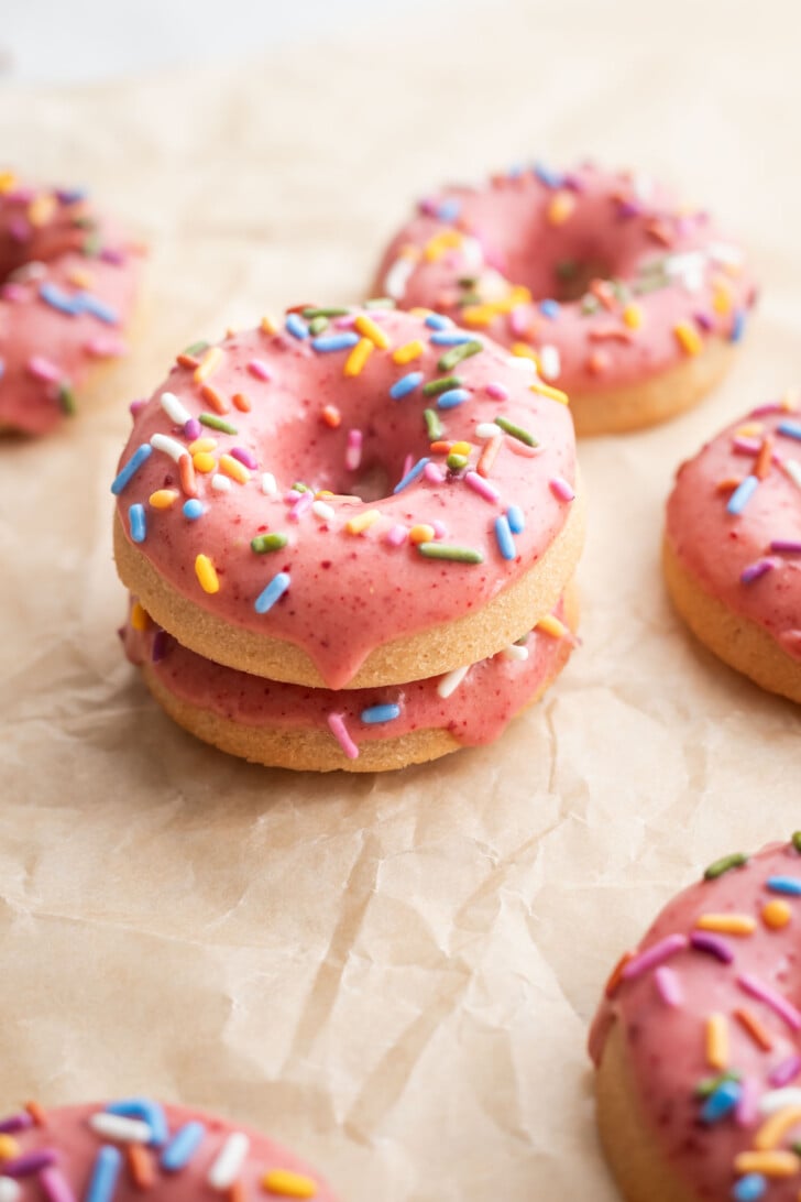 Baked strawberry mochi donuts stacked on each other on parchment paper.