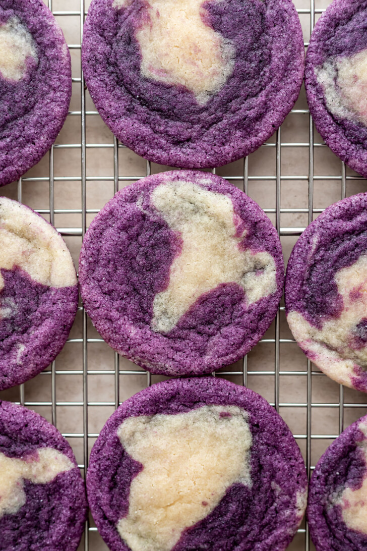 Purple and white marbled cookies cooling on a metal wire rack, arranged in neat rows. The cookies have a swirled pattern, with vibrant purple and creamy white colors blending together.