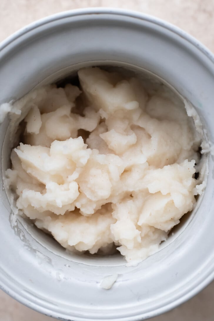 A close-up view of a ice cream bowl filled with lychee sorbet. The white bowl is placed on a neutral-colored surface.