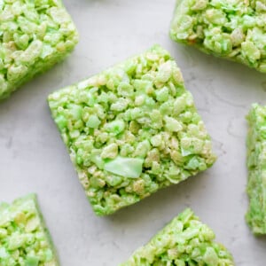 Close-up of green pandan rice krispie cereal treats cut into squares and arranged on a light surface.
