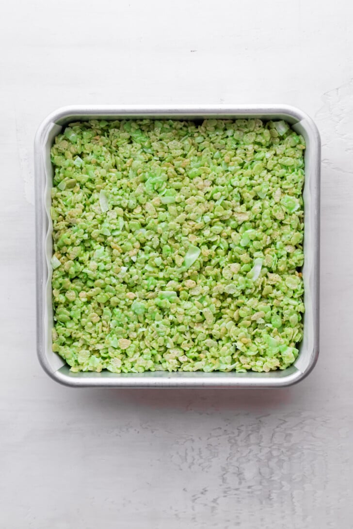 A square baking pan filled with green pandan Rice Krispies treats, viewed from above on a white surface.
