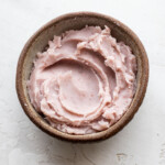 A small brown bowl filled with lavender taro paste placed on a textured white surface.