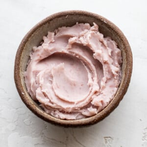 A small brown bowl filled with lavender taro paste placed on a textured white surface.