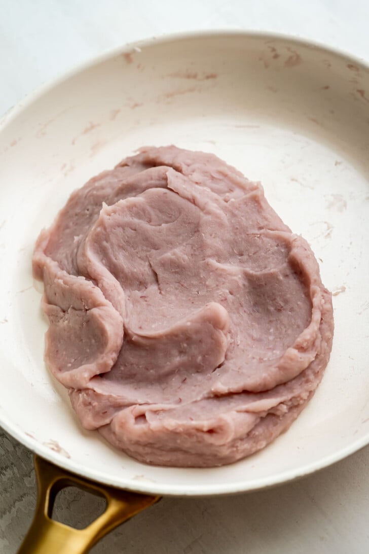 A pan containing a smooth, pinkish-purple taro paste spread evenly across the fry pan.