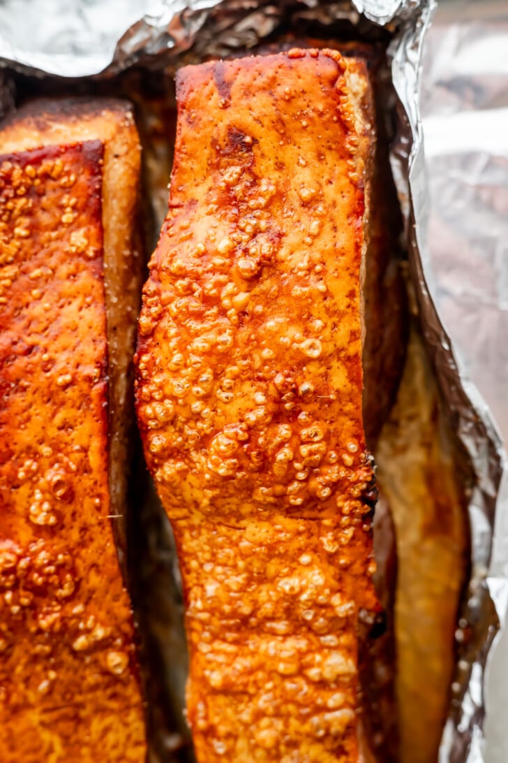 Close-up of air fryer crispy pork belly skin with golden-brown bubbles, resting on aluminum foil, highlighting the juicy texture and perfectly cooked meat.